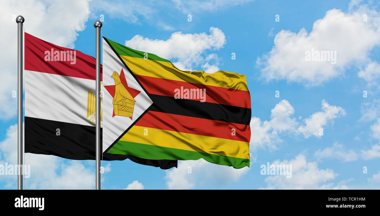 L'Egypte et le Zimbabwe drapeaux dans le vent contre ciel bleu nuageux blanc ensemble. Concept de diplomatie, de relations internationales. Banque D'Images