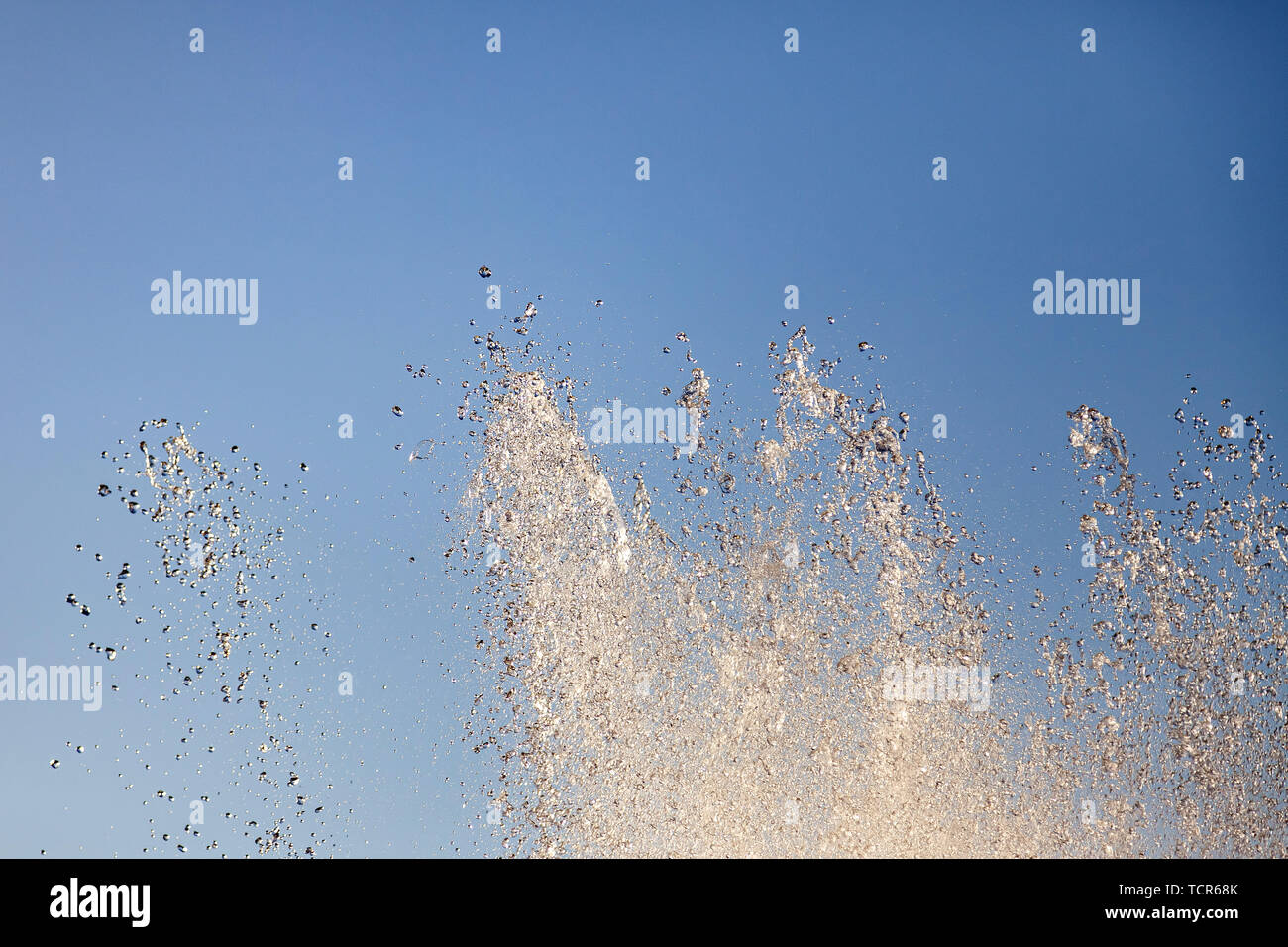 Close-up sur les éclaboussures sur les cours d'eau d'une fontaine artificielle à partir de laquelle l'eau s'écoule en gouttes dans le parc de la ville contre le ciel bleu sur un été chaud Banque D'Images