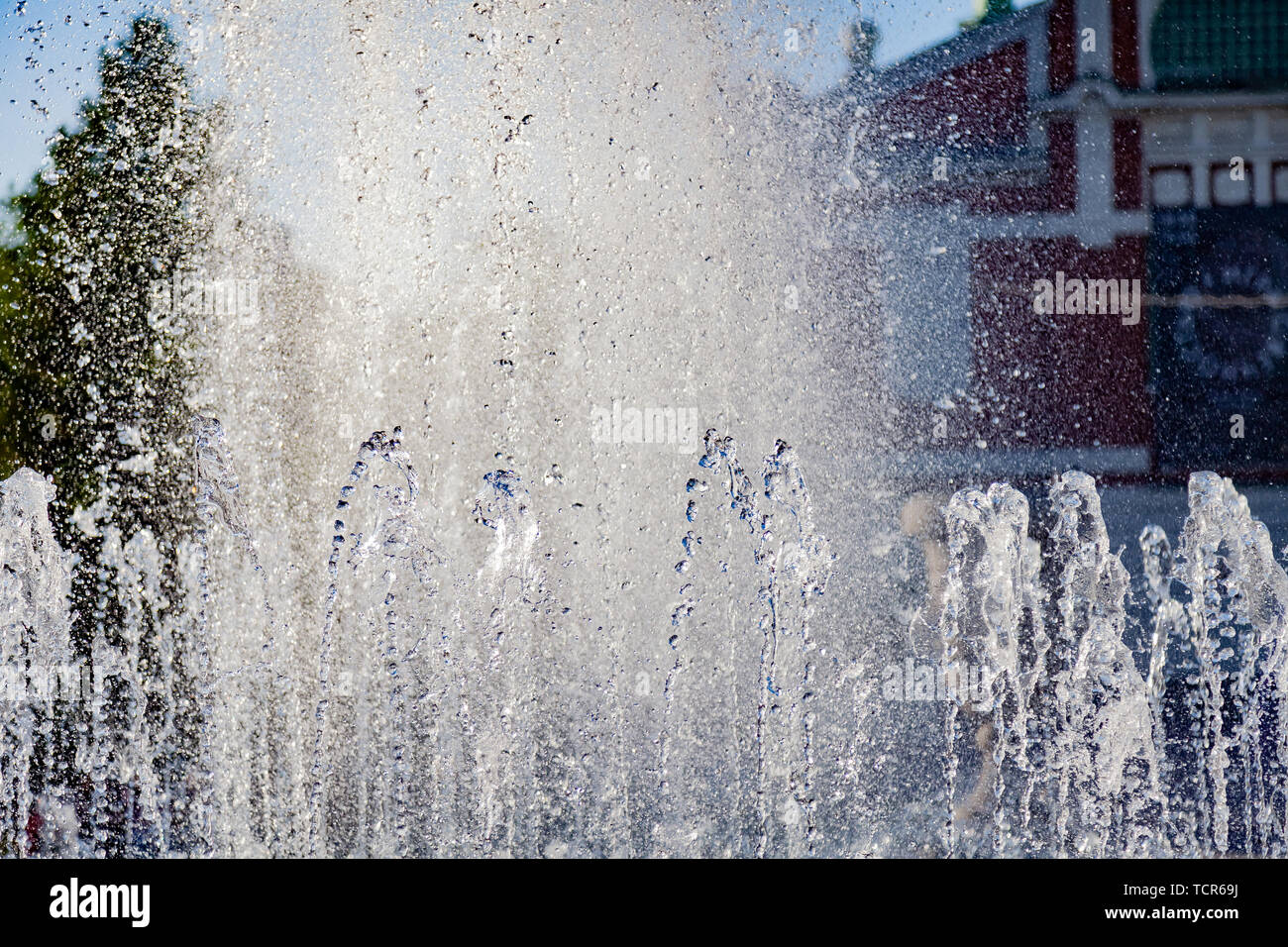 Close-up sur les éclaboussures de jets d'une fontaine artificielle à partir de laquelle l'eau s'écoule en gouttes dans un parc de la ville dans le contexte d'un vieux bâtiment o Banque D'Images