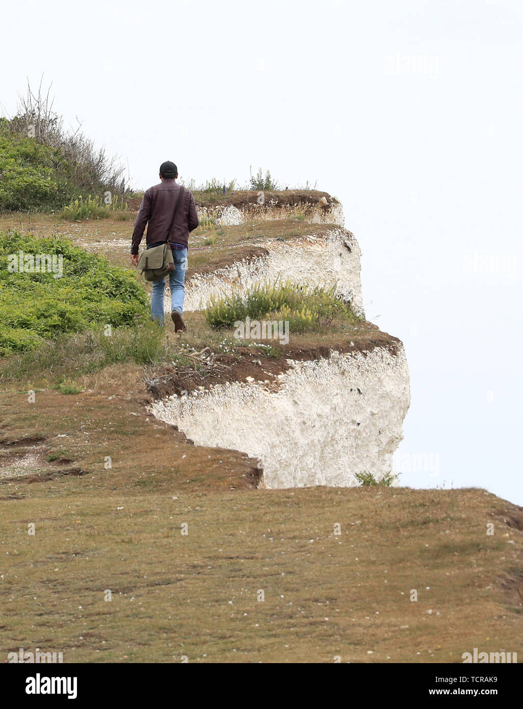 Un homme marche le long du bord de la falaise à Urrugne près d'Eastboune, Sussex, que les avertissements sont ignorées sur les dangers de l'effondrement des falaises de craie qui peuvent s'effondrer sans avertissement. Banque D'Images