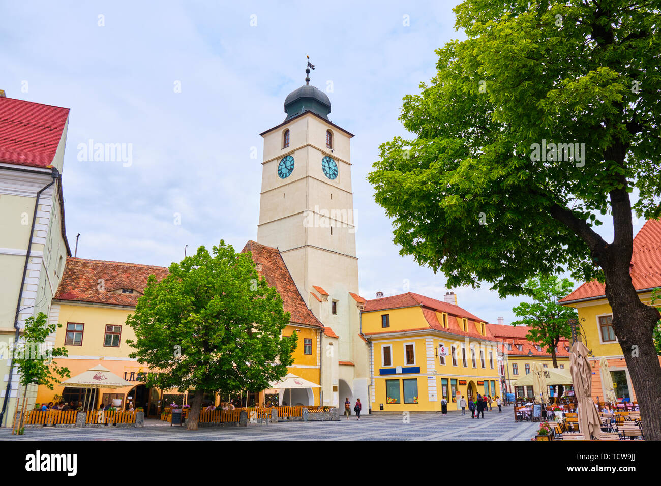 Sibiu, Roumanie - 27 mai 2019 : La tour du Conseil (Turnul Sfatului) à Sibiu, vu de la grande place, avec des arbres verts par temps nuageux jour. Popula Banque D'Images
