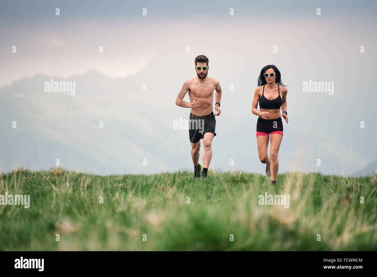 L'homme et de la femme sportive courir chaud en été sur hill meadows Banque D'Images