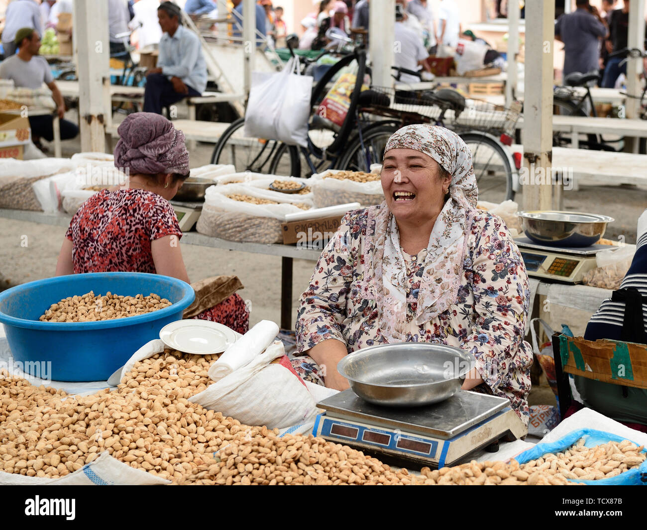 Marguilan, vallée de Ferghana, en Ouzbékistan - 2 juin 2019 : vente femme ouzbèke, amandes et arachides dans l'arrière-plan Marguilan marché. Banque D'Images