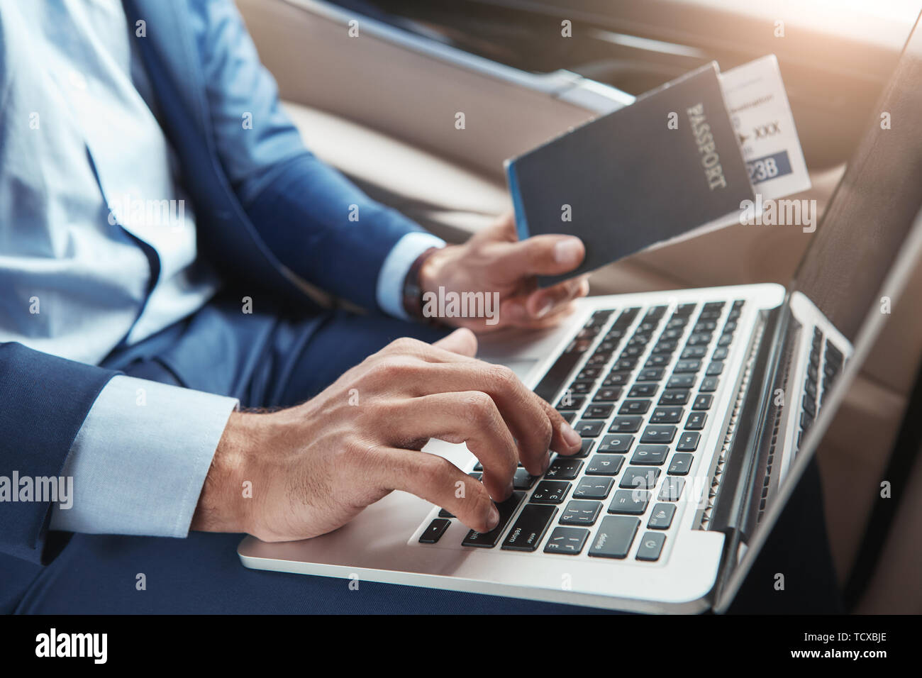 À l'hôtel. Portrait of businessman working on laptop usure formelle et holding passport avec billets de vol tout en restant assis dans la voiture. Voyage Banque D'Images