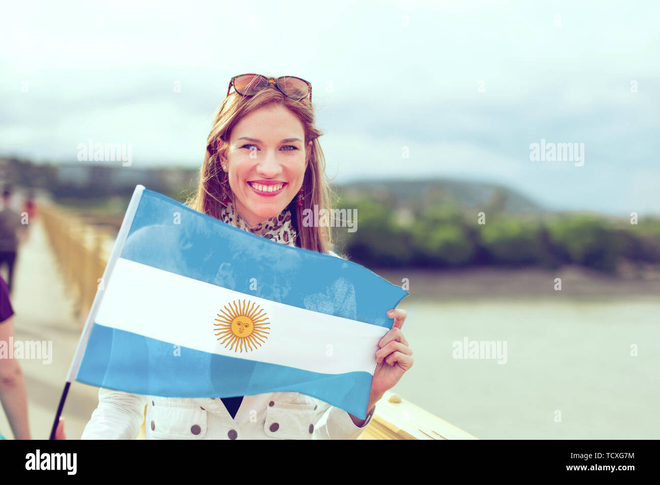Jeune femme tenant un drapeau de l'Argentine avec sourire à pleines dents, à l'extérieur, couleur classés Banque D'Images