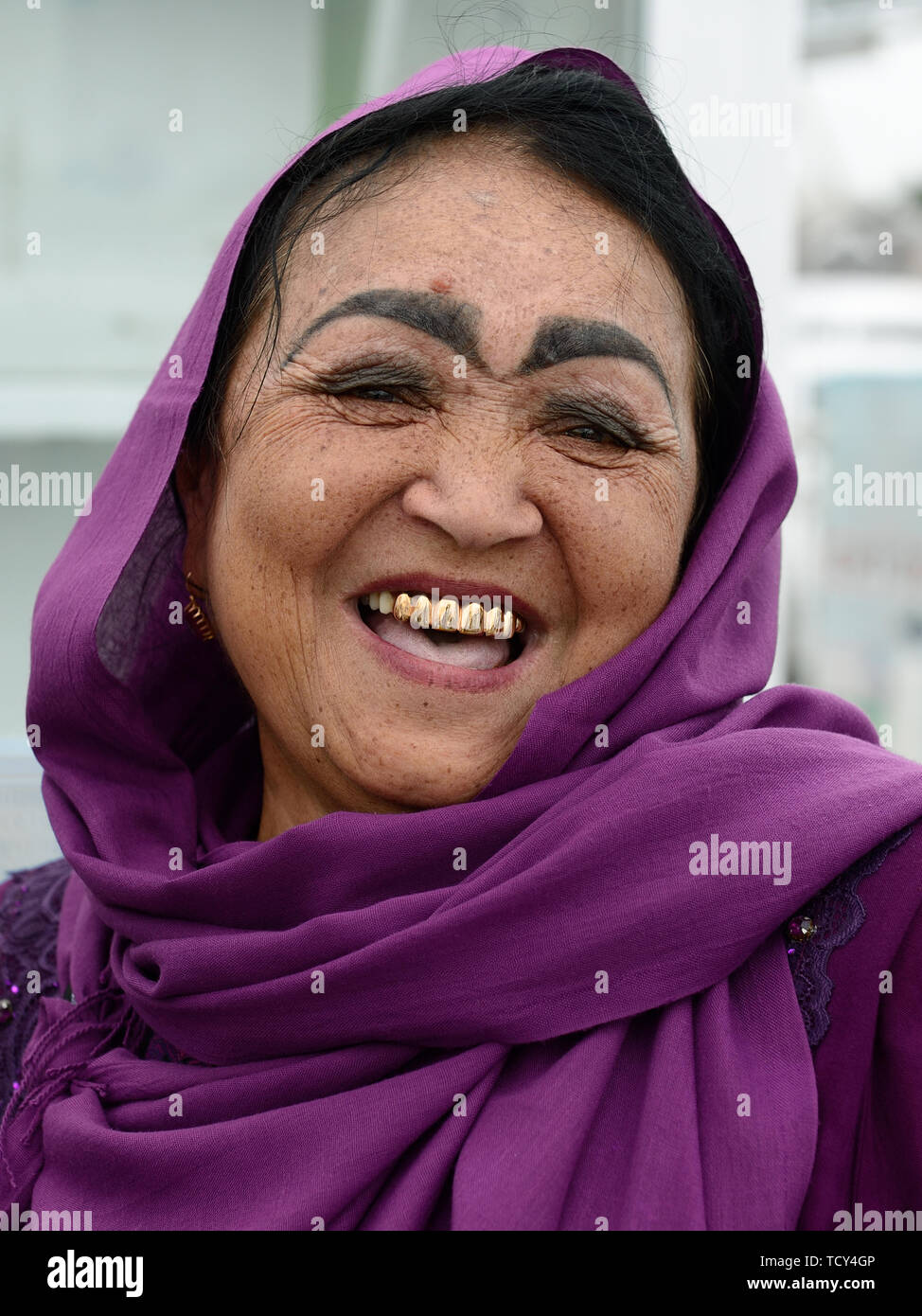Marguilan, vallée de Ferghana, en Ouzbékistan - 2 juin 2019 : Portrait de la femme ouzbèke rire, habillés dans l'écharpe, avec l'incroyable composition de l'e Banque D'Images