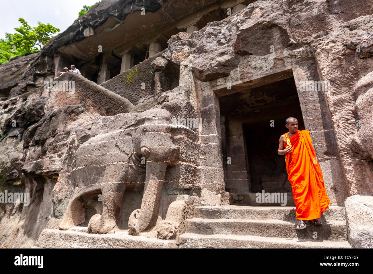 Le moine bouddhiste dans l'entrée escalier de la grotte d'un étage, avec 16 éléphants en pierre, grottes d'Ajanta Aurangabad, Maharashtra, Inde, état Banque D'Images
