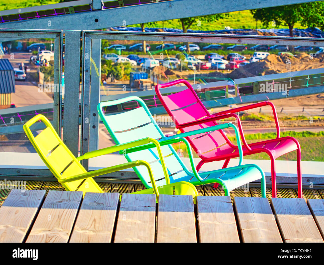 Style de décoration moderne. Trois métal de couleur jaune, rose et vert de chaises sur terrasse en bois, style extérieur avec mobilier et d'objets colorés. Conce Banque D'Images