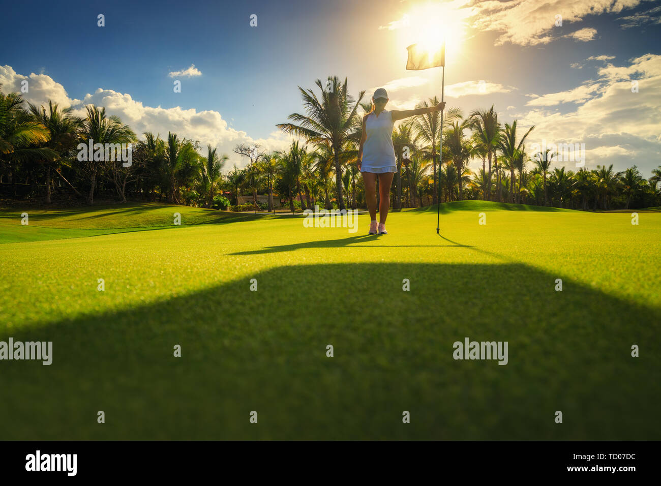 Jeune femme debout sur golfeur golf tropical, , reflets de soleil en soirée. Banque D'Images