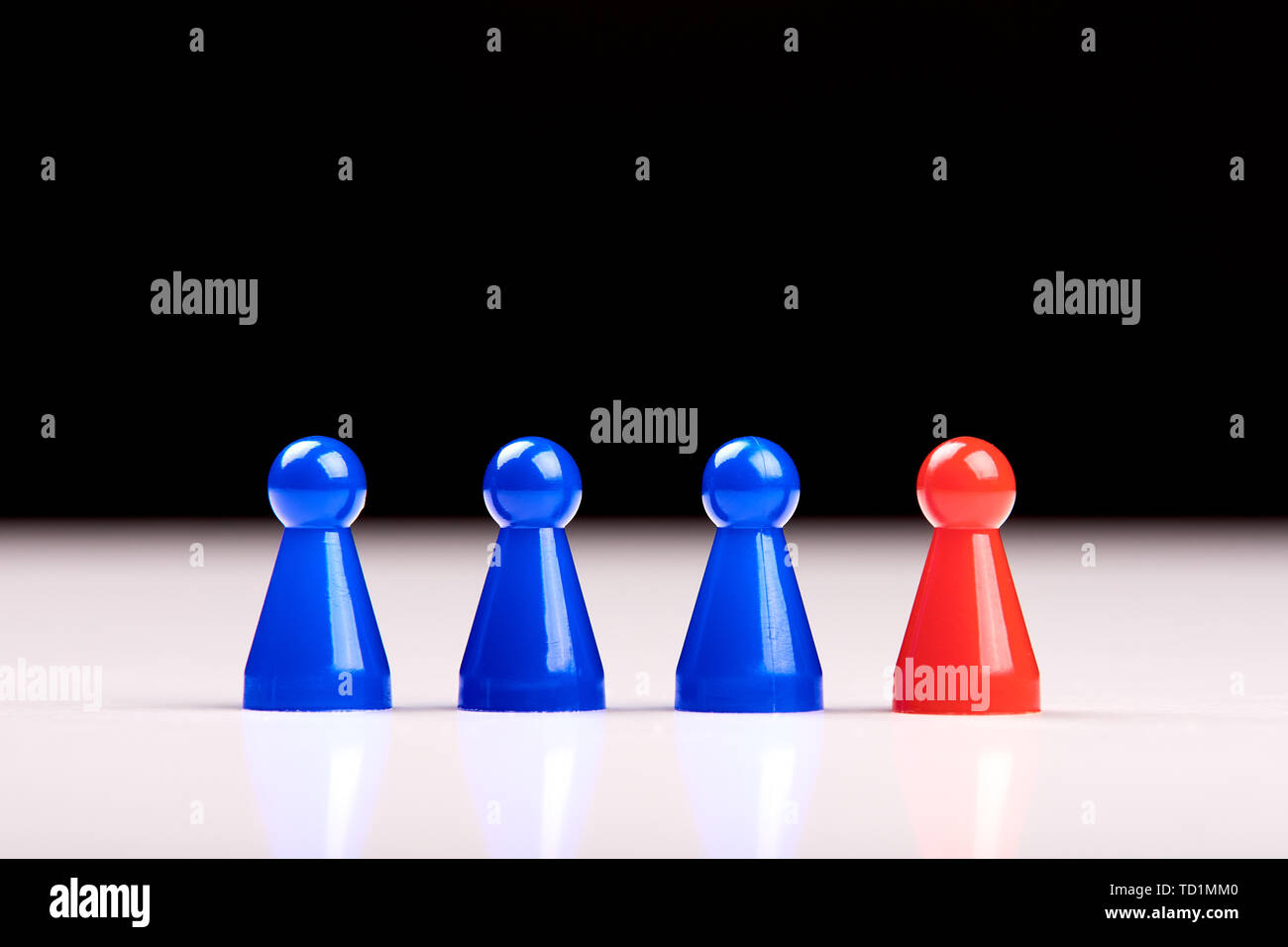 Trois pièces de jeu bleu et un chiffre rouge debout à côté d'eux comme un chef, patron ou différents. Floue fond noir et blanc. Banque D'Images