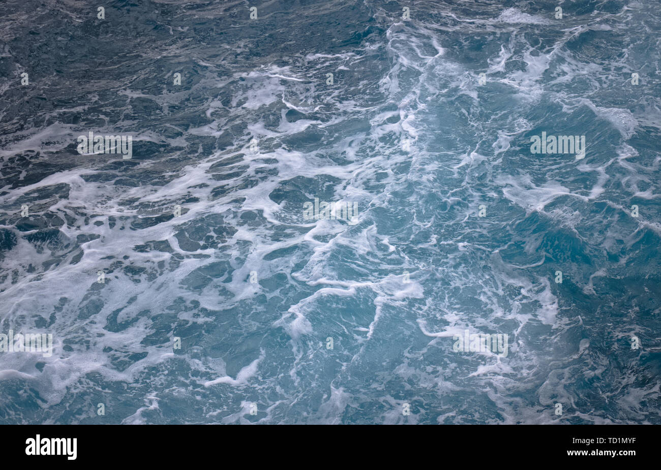 Les vagues de l'océan bleu blanc créant des tourbillons mousseux vu de dessus. Banque D'Images