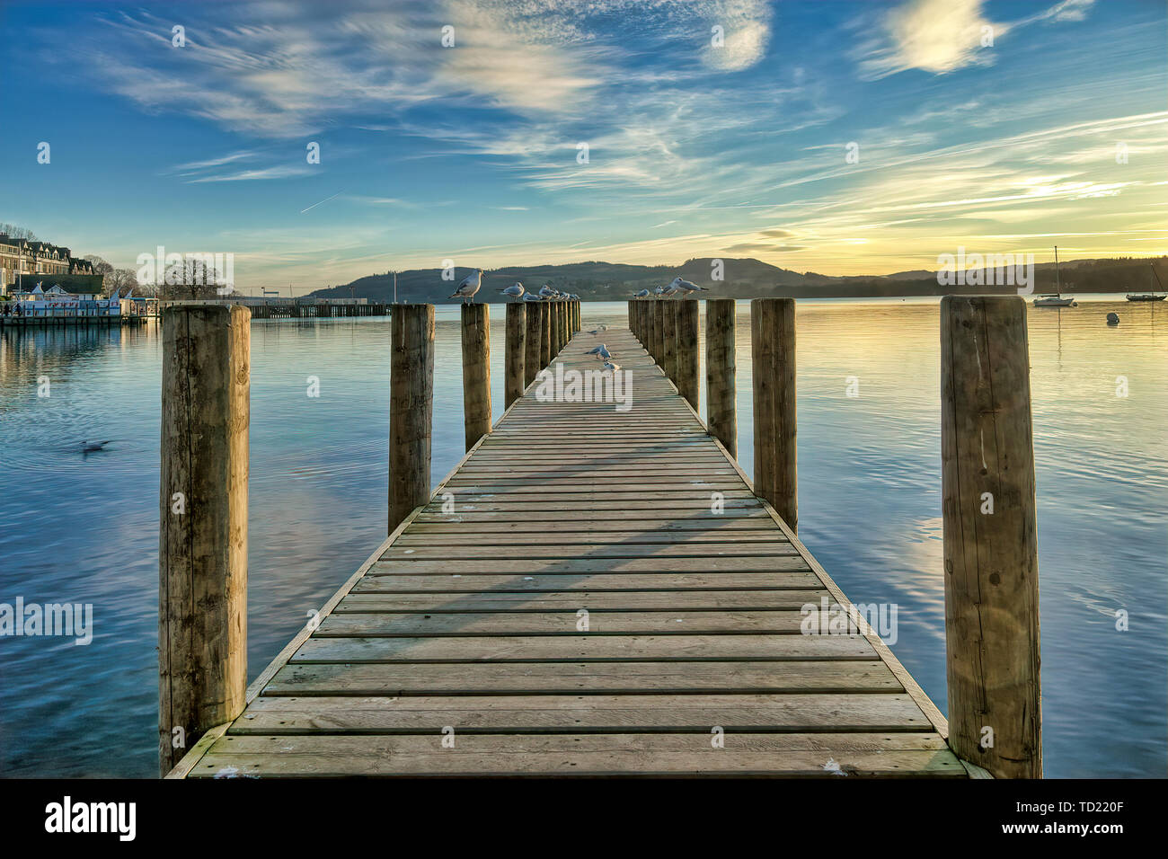 Une jetée sur une calme Windermere au coucher du soleil. Banque D'Images