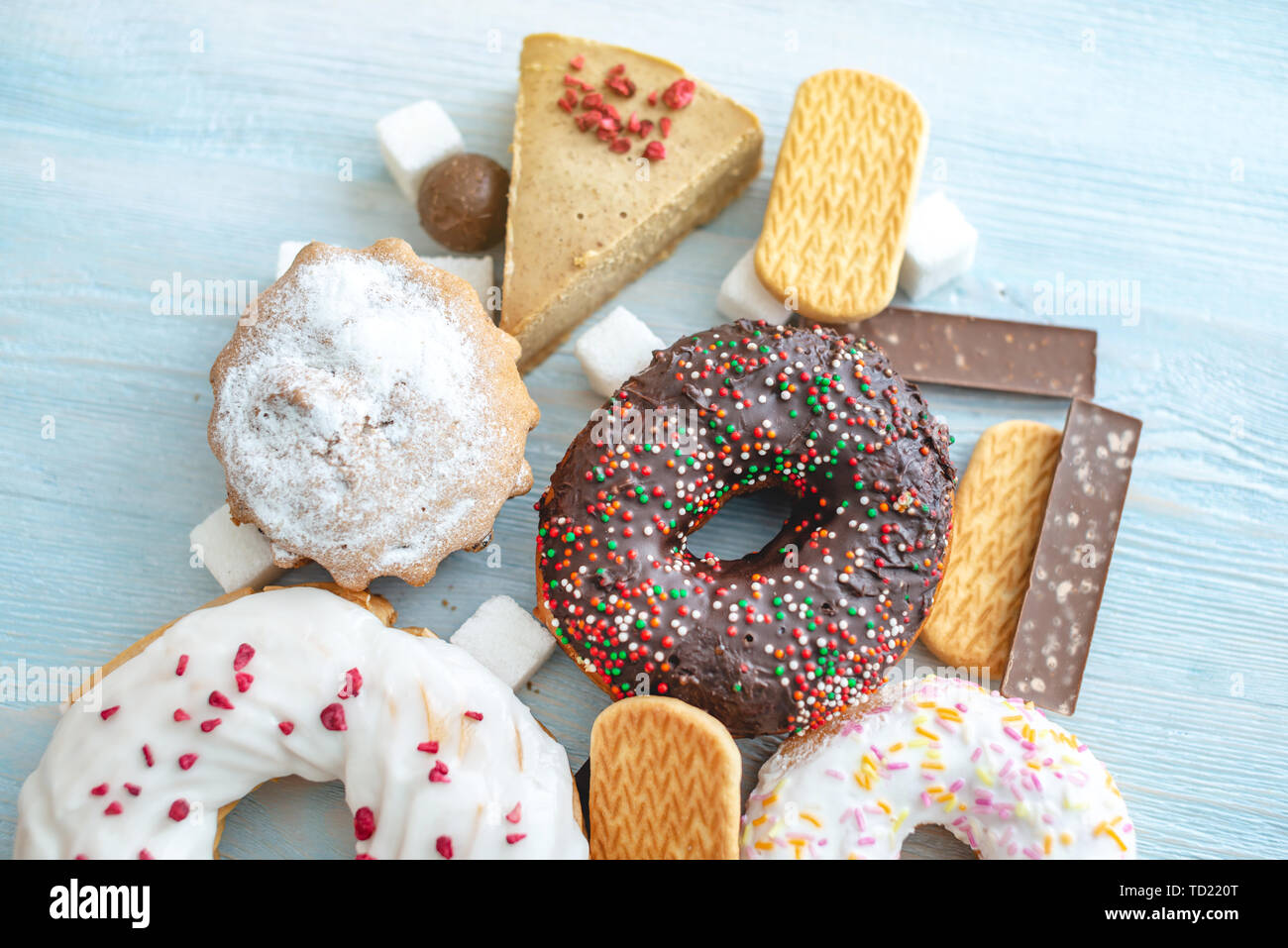 Les aliments sucrés nuisibles on blue background. Beignes, muffins, des chocolats sur la table pile. La notion de mauvaise alimentation et de l'embonpoint. Le point de vue f Banque D'Images