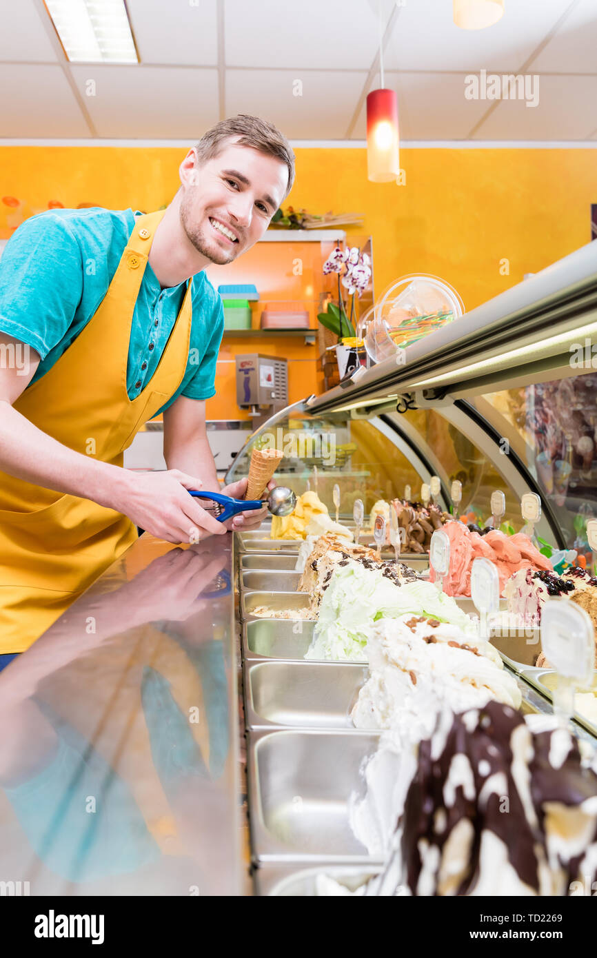 Vendeur de crème glacée dans sa boutique au comptoir avec beaucoup de saveurs au choix Banque D'Images