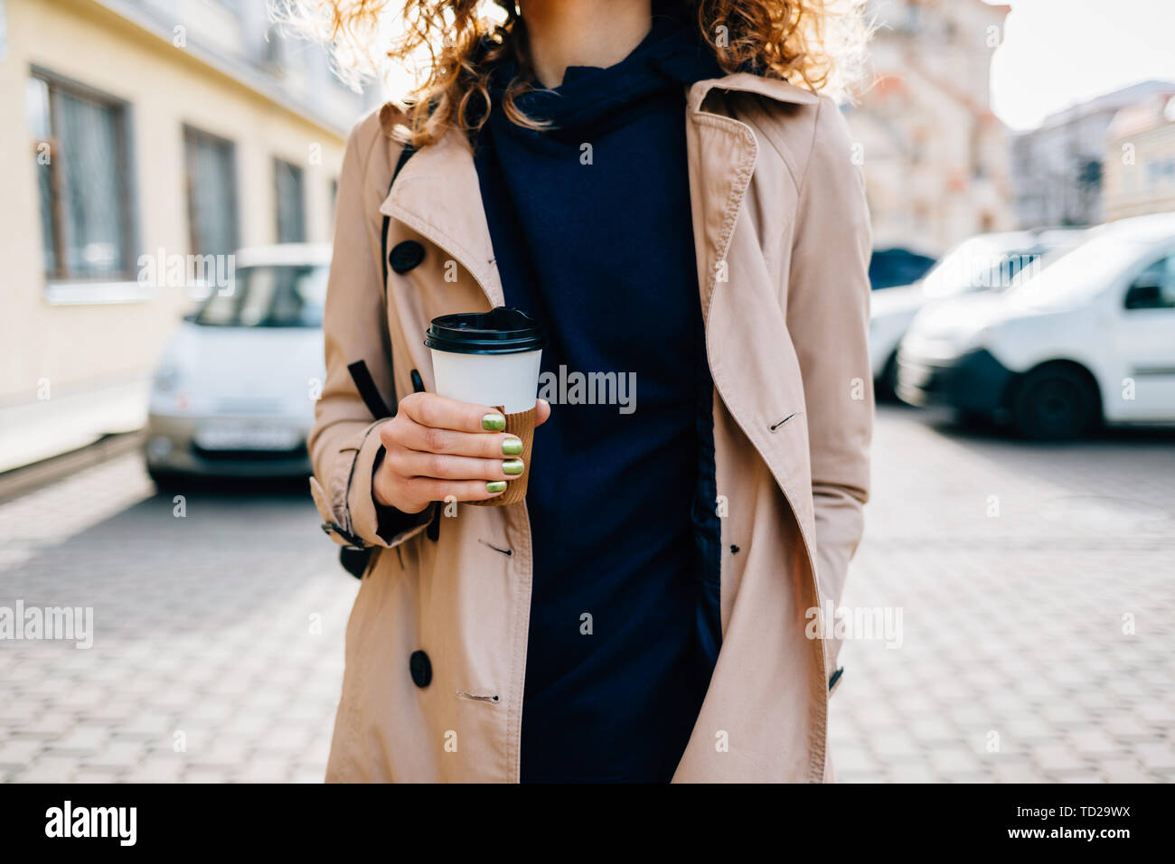 Close-up elegant young woman holding tasse de café chaud à la main debout sur la rue de la ville. Banque D'Images