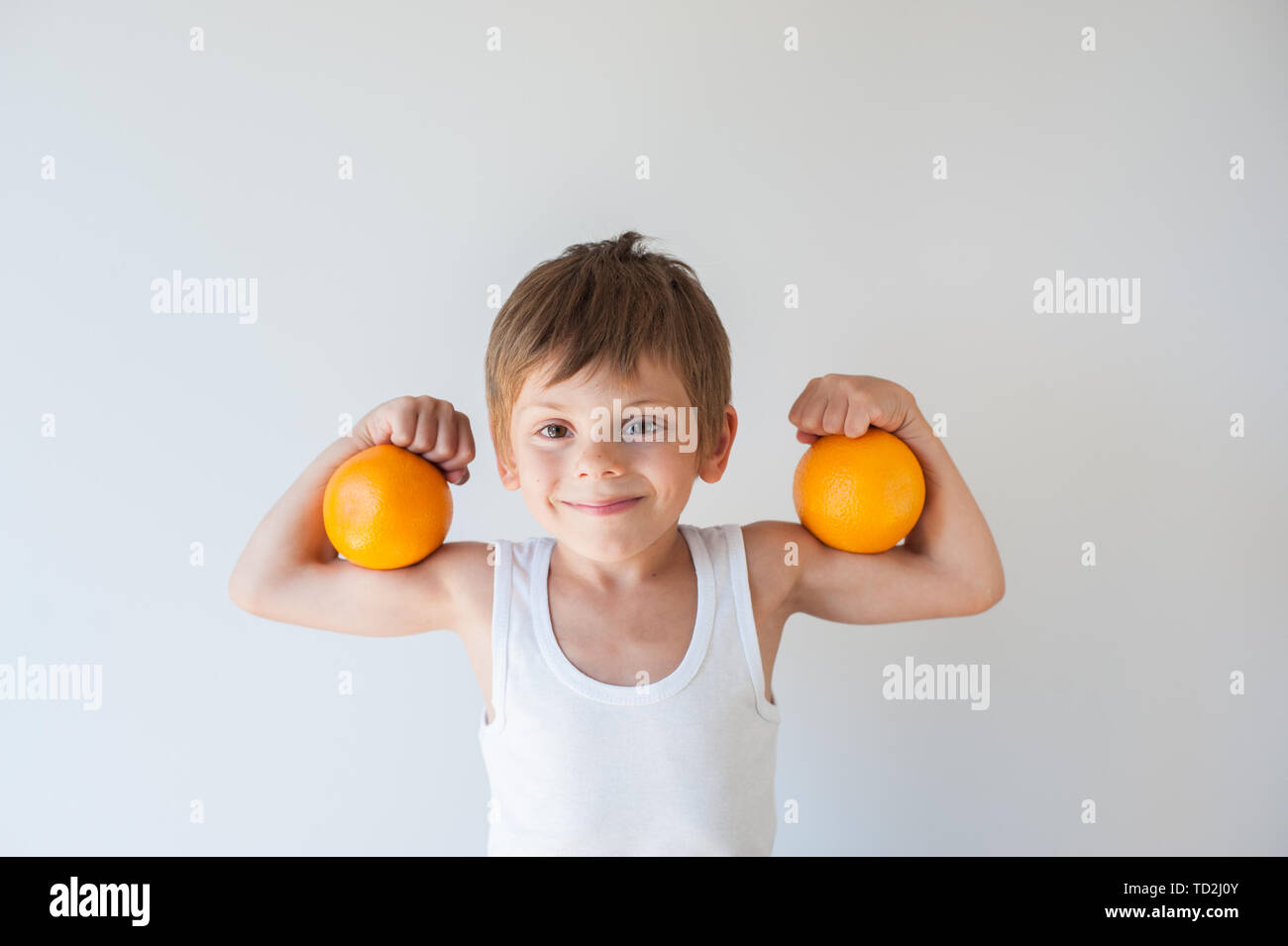 Mignon Petit Enfant Sain En Debardeur Blanc Tenant Deux Fruits Orange Sur Son Muscle Biceps Photo Stock Alamy Mignon Petit Enfant Sain En Debardeur Blanc Tenant Deux Fruits Orange Sur Son Muscle Biceps Photo Stock Alamy