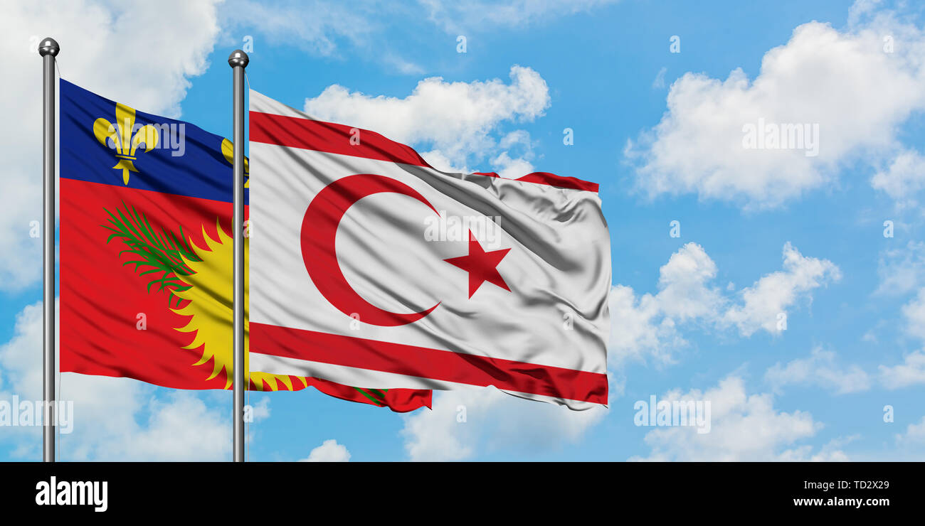 La Guadeloupe et la Chypre du Nord drapeaux dans le vent contre ciel bleu nuageux blanc ensemble. Concept de diplomatie, de relations internationales. Banque D'Images