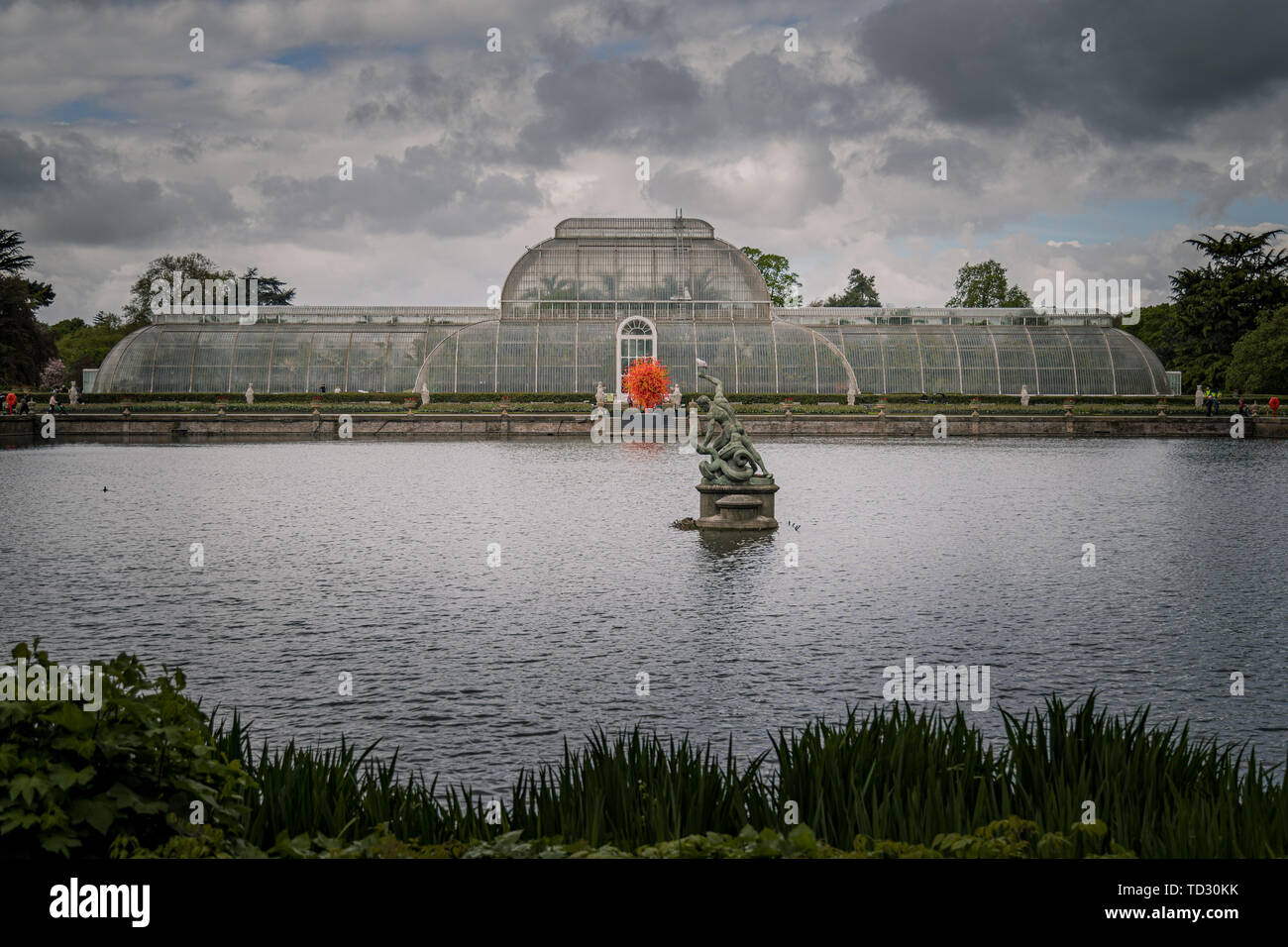 Le point de vue de la Palm House à partir de l'autre côté de l'eau à Kew Gardens avec la sculpture en verre soufflé été Soleil par Dale Chihuly en face d'elle. Banque D'Images