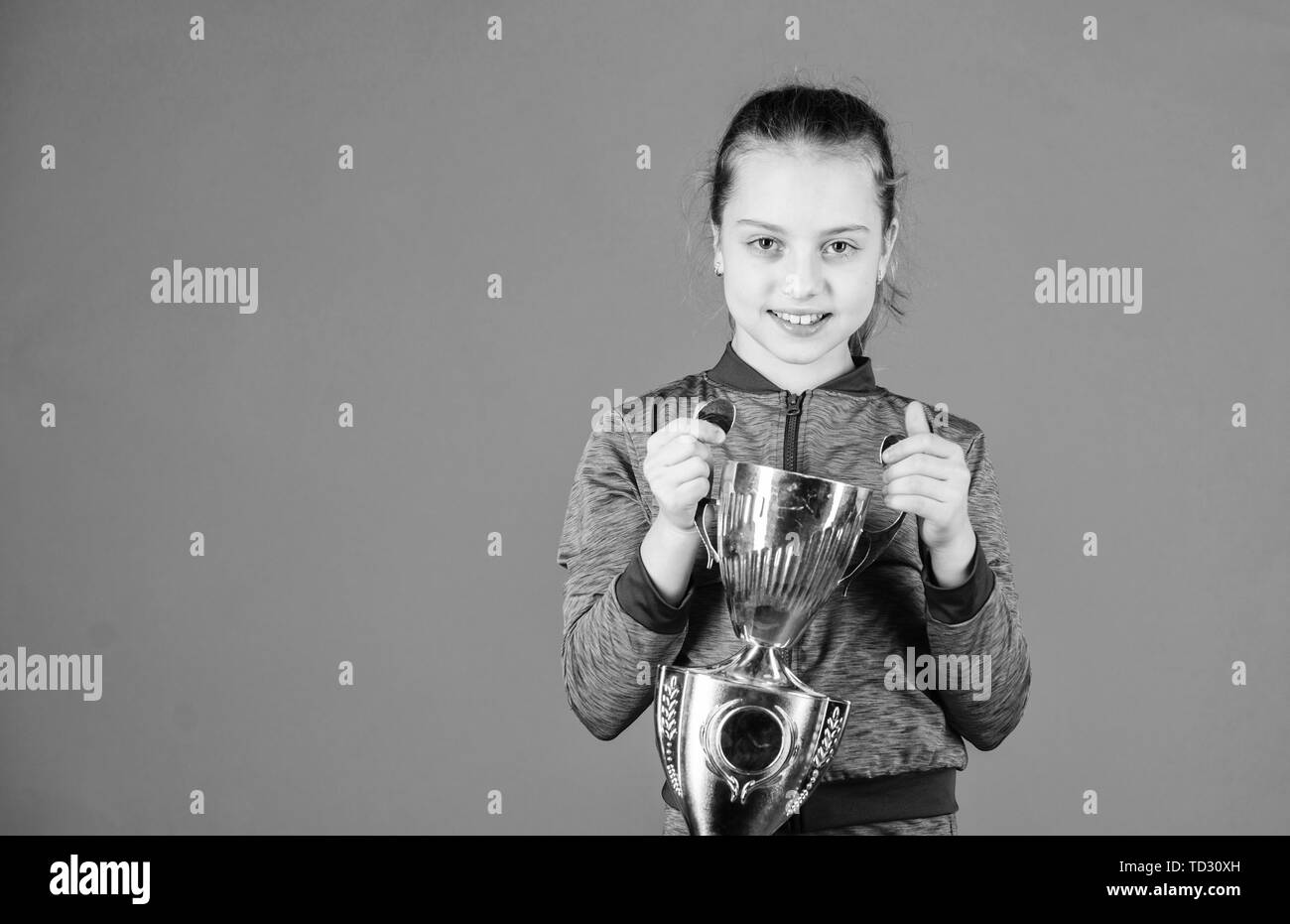 Elle est la meilleure. Petite fille holding silver cup. Petit enfant en forme de tasse avec trophée sportif. L'attribution de l'athlète mignon avec tasse. Adorable vainqueur de la coupe du monde, l'espace de copie. Banque D'Images