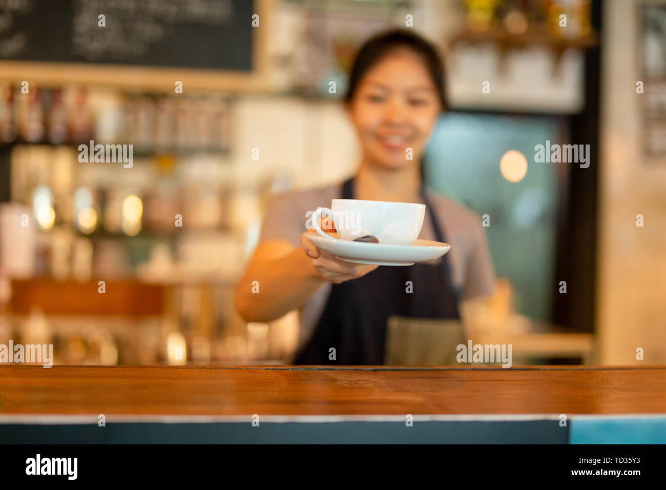 Femme asiatique qui sert du café barista tasse à café à la clientèle. Banque D'Images