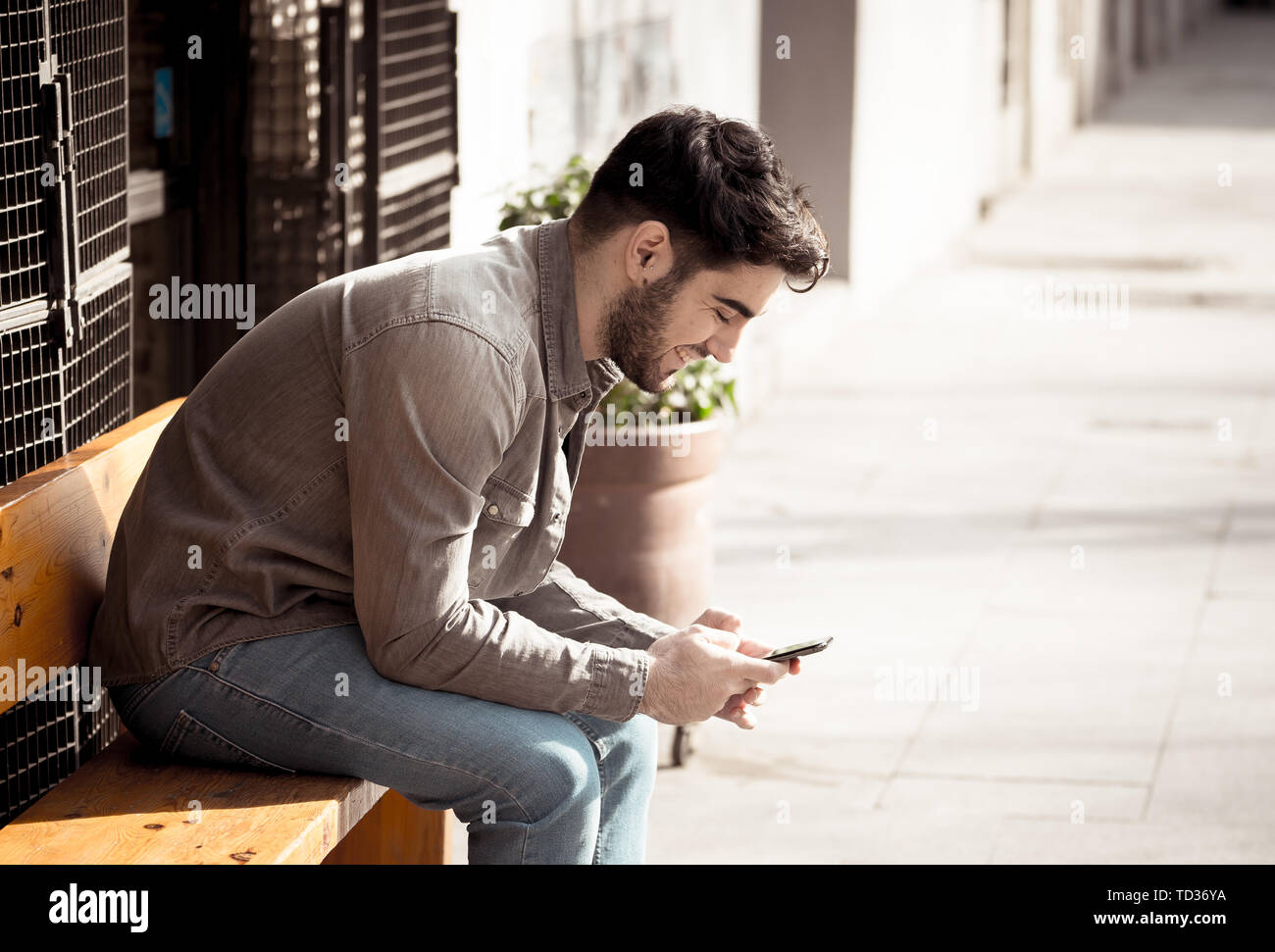Collège de la mode homme d'une vingtaine d'heureux blog contrôle et de chatter sur internet avec des amis sur smart mobile phone app en plein air européen ville. Banque D'Images