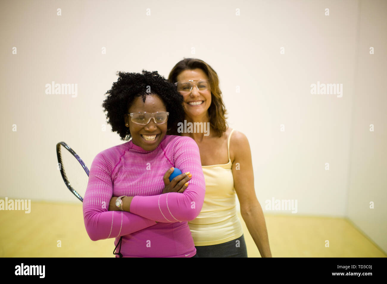 Portrait de deux femmes souriant debout sur un court de racquetball. Banque D'Images