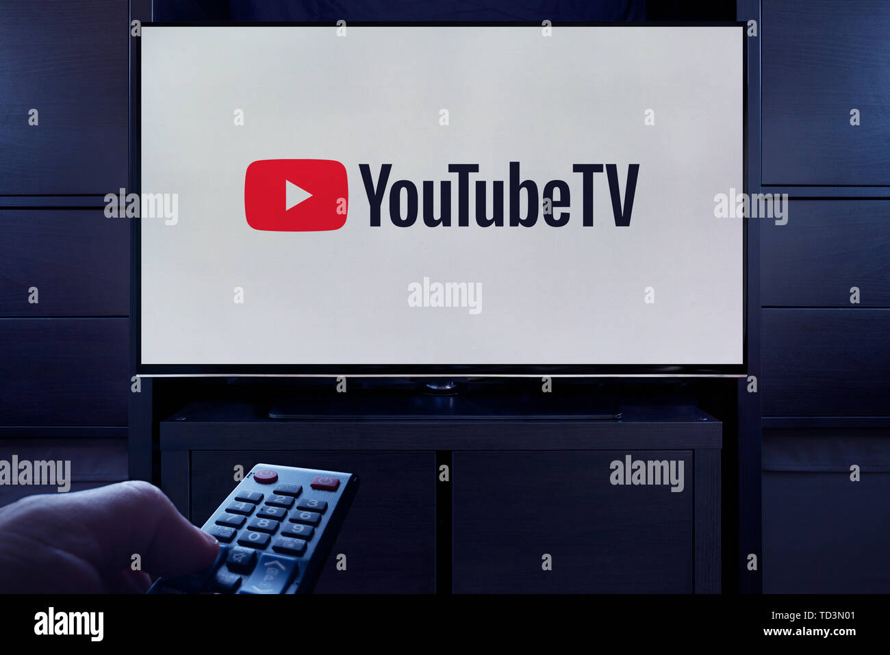 Un homme d'un points TV remote à la télévision qui affiche le logo de la télé à la demande YouTube video streaming service (usage éditorial uniquement). Banque D'Images