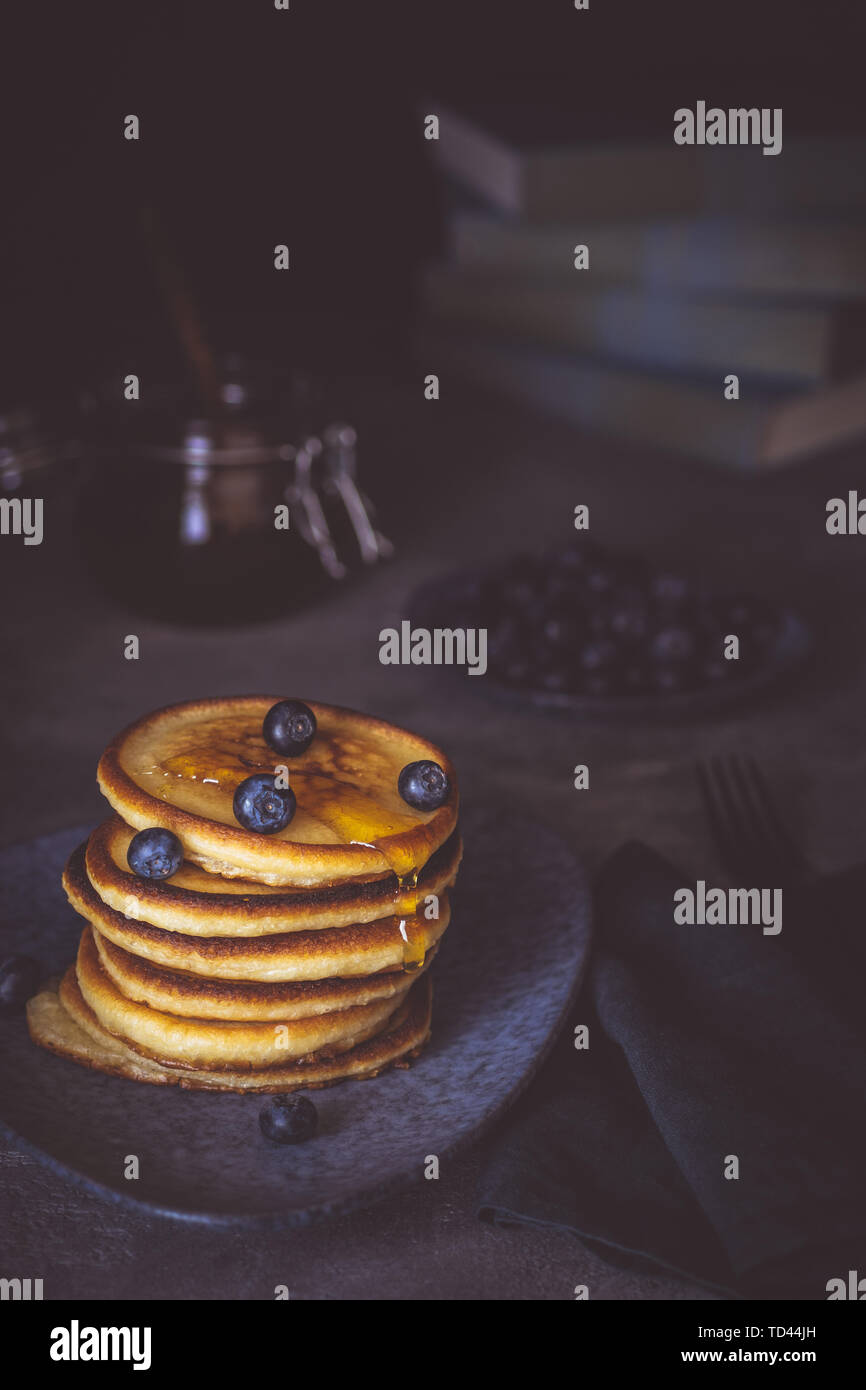 Des pancakes avec du sirop d'érable biologique et de baies sur fond sombre Petit-déjeuner américain classique Banque D'Images