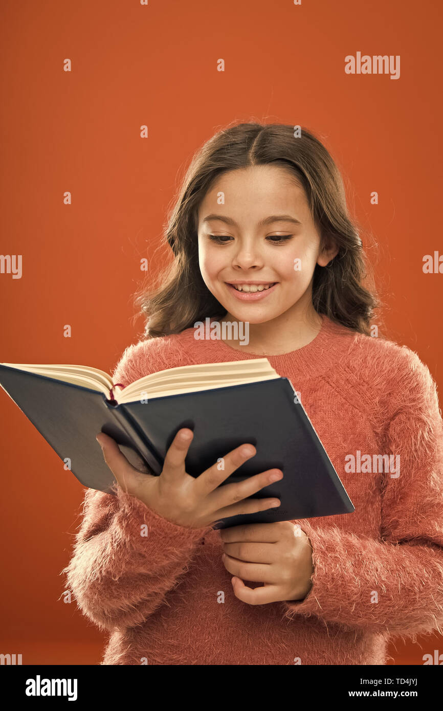 Entraînement à la lecture pour les enfants. Fille tenir livre lu story sur  fond orange. Enfant aime lire livre. Concept de magasin de livre. De  merveilleux livres pour enfants disponibles à lire.