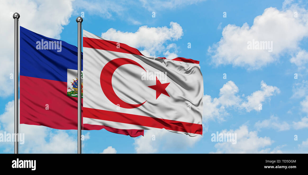 Haïti et la Chypre du Nord drapeaux dans le vent contre ciel bleu nuageux blanc ensemble. Concept de diplomatie, de relations internationales. Banque D'Images