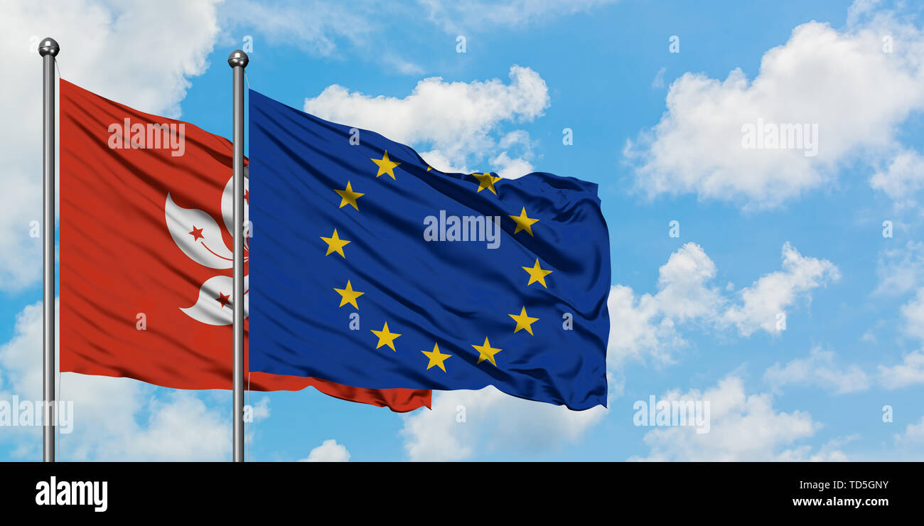 Hong Kong et de l'Union européenne drapeaux dans le vent contre ciel bleu nuageux blanc ensemble. Concept de diplomatie, de relations internationales. Banque D'Images