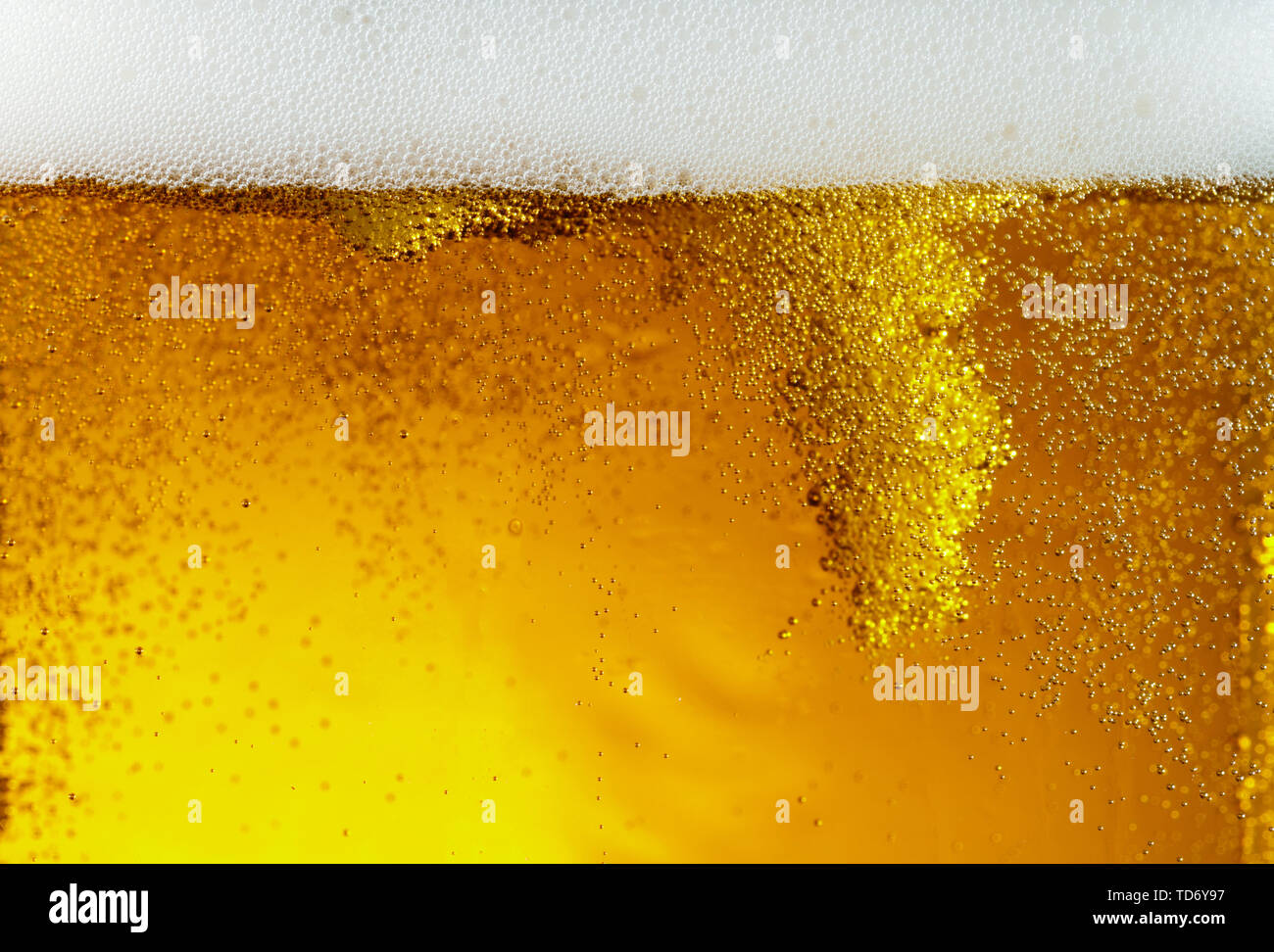 Vue rapprochée de bulles flottantes en bière de couleur d'or léger arrière-plan. La texture de l'été de refroidissement verre filtré avec mousse et macro fizz sur le mur de verre. L'effervescence ou flottant jusqu'au-dessus de la surface. Banque D'Images