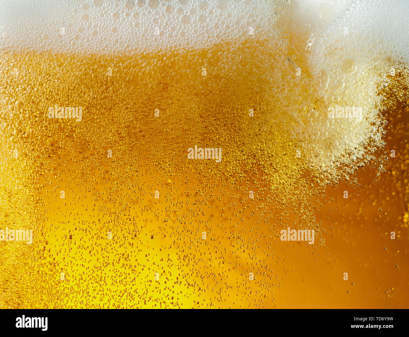 Vue rapprochée de bulles flottantes en bière de couleur d'or léger arrière-plan. La texture de l'été de refroidissement verre filtré avec mousse et macro fizz sur le mur de verre. L'effervescence ou flottant jusqu'au-dessus de la surface. Banque D'Images