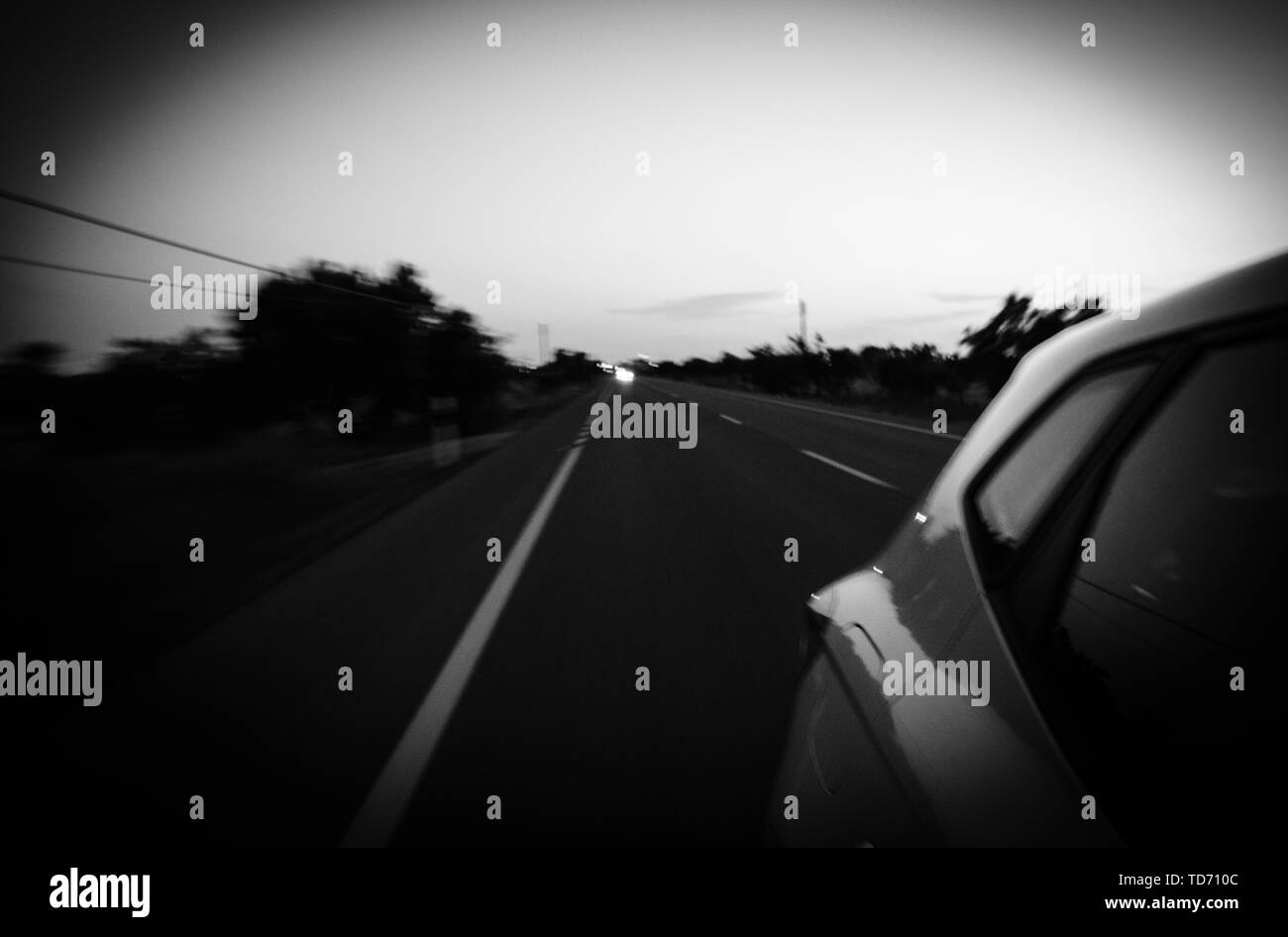 Vue depuis la voiture conduite rapide sur l'autoroute de l'espagnol au crépuscule avec des voitures à la suite sur l'autoroute - noir et blanc Banque D'Images