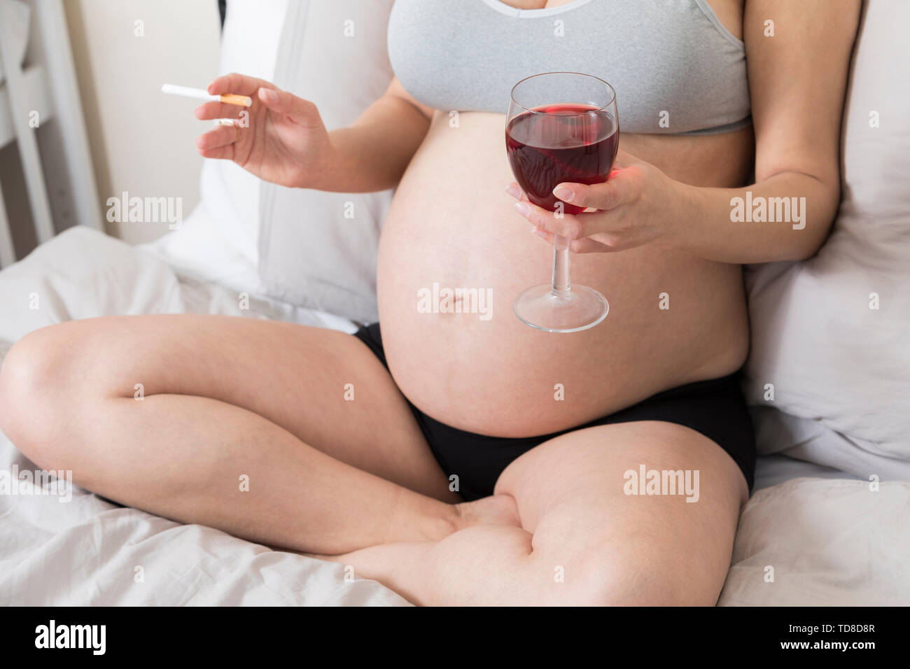 Jeune femme enceinte fumant des cigarettes et buvant de l'alcool, femmes enceintes avec du tabac et du verre de vin, mauvaises habitudes et abus Banque D'Images