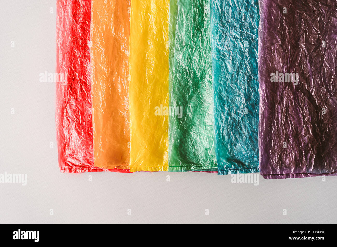 Les sacs de plastique à une ligne par les couleurs de l'arc-en-ciel sur fond gris. Banque D'Images