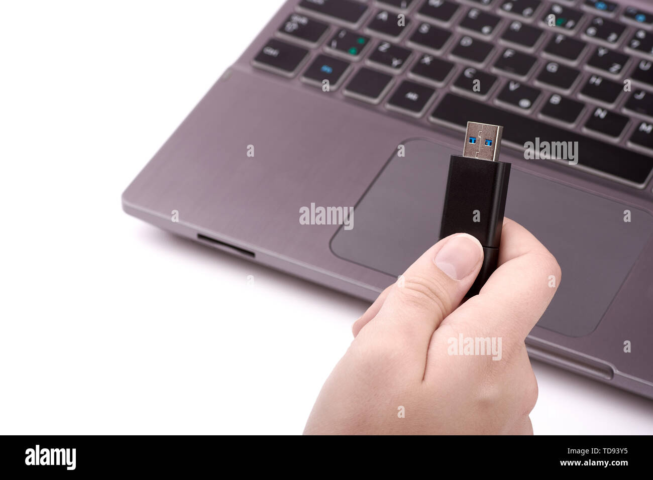 Jeune femme tenant un lecteur flash USB noir à la main, avec un coffre d'argent flou artistique avec un clavier à l'arrière-plan. Isolé sur blanc backgroun Banque D'Images