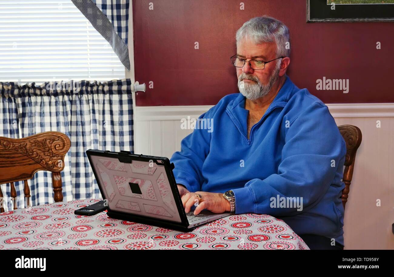 Senior Citizen heureux à l'aide d'un ordinateur et de la technologie à faire des activités quotidiennes Banque D'Images