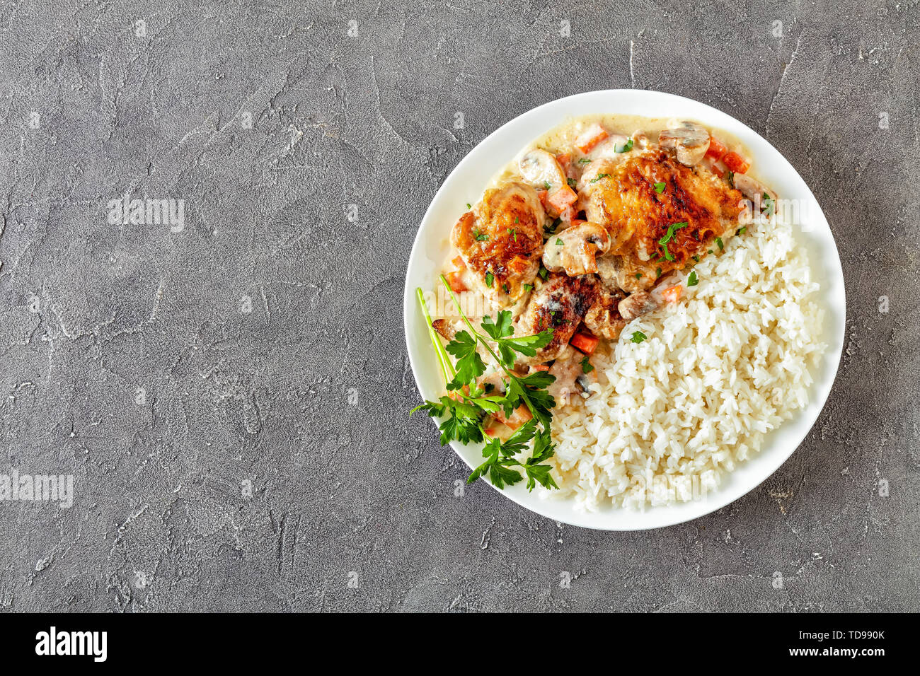 Compotée de poulet avec sauce au vin blanc crème, champignons et légumes et servi avec du riz sur une plaque sur une table en béton - Fricassée de poulet, de classe Banque D'Images