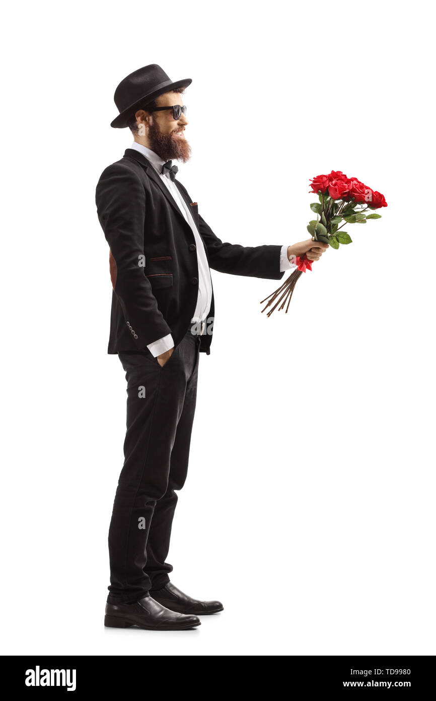 Profil de toute la longueur d'un homme en costume donnant un bouquet de roses rouges isolé sur fond blanc Banque D'Images