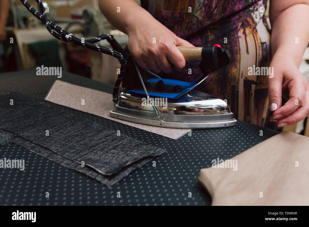 Une femme caresse la toile pour plus de couture. Le repassage des vêtements  sur mesure avec fer à repasser industriel Photo Stock - Alamy