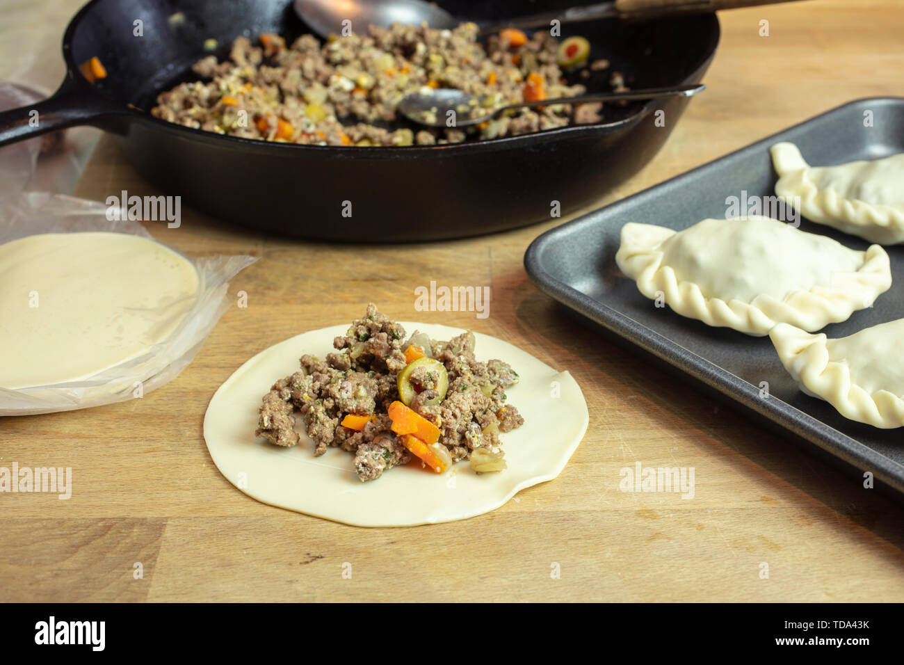 Préparation des empanadas argentines avec un boeuf haché, olives, carrouts et épices farce mis sur la pâte et leur formation continue à cuire sur un pa Banque D'Images