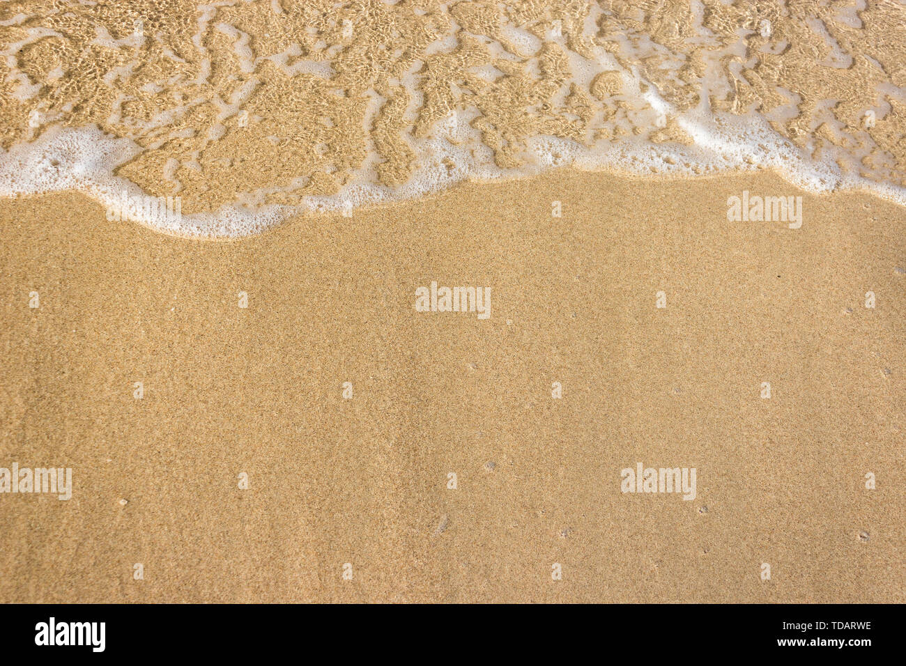 Vagues douces avec de la mousse de l'océan sur la plage de sable contexte Banque D'Images