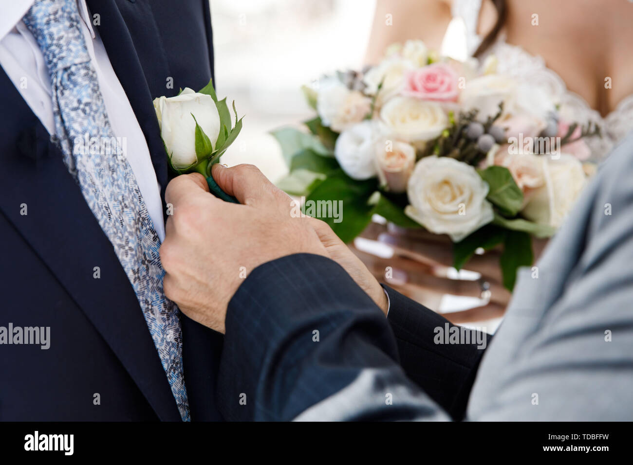 Après la cérémonie de mariage, le marié est serrant dans ses bras une petite rose sur une veste. Vacances romantiques Banque D'Images