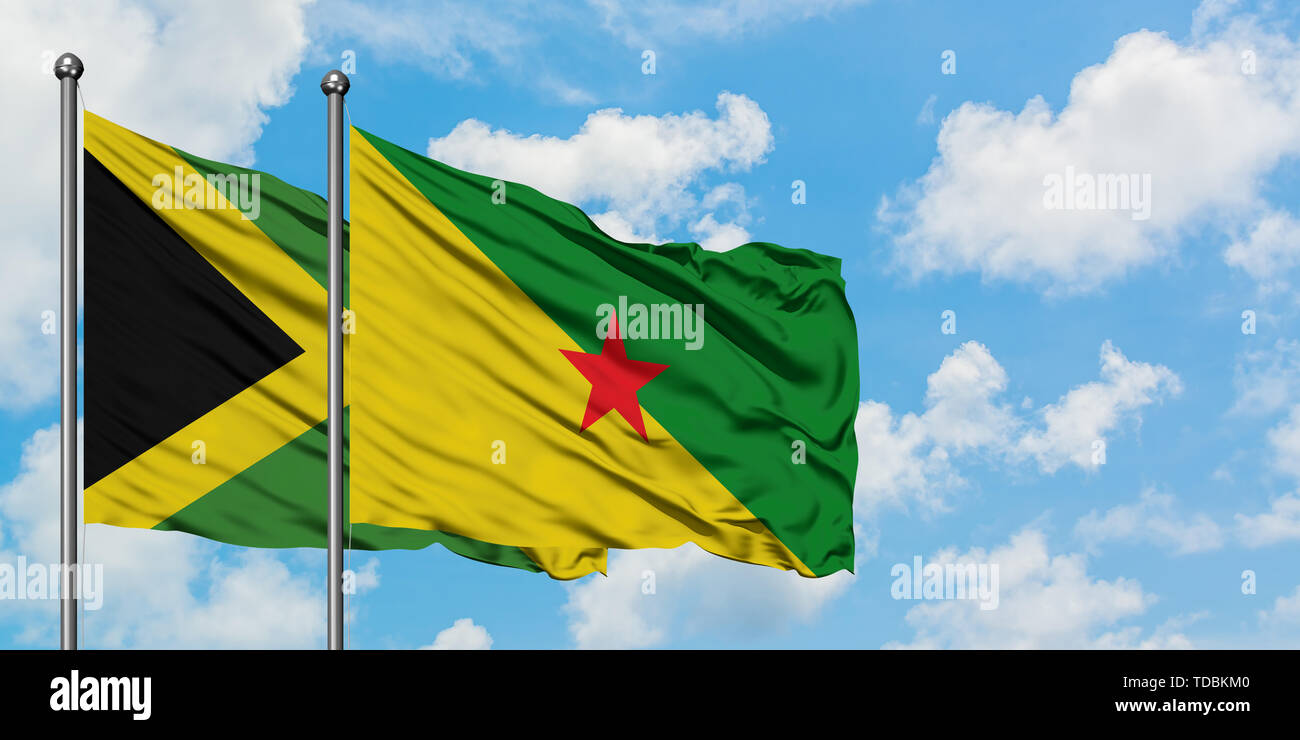 La Jamaïque et Guyane drapeaux dans le vent contre ciel bleu nuageux blanc ensemble. Concept de diplomatie, de relations internationales. Banque D'Images