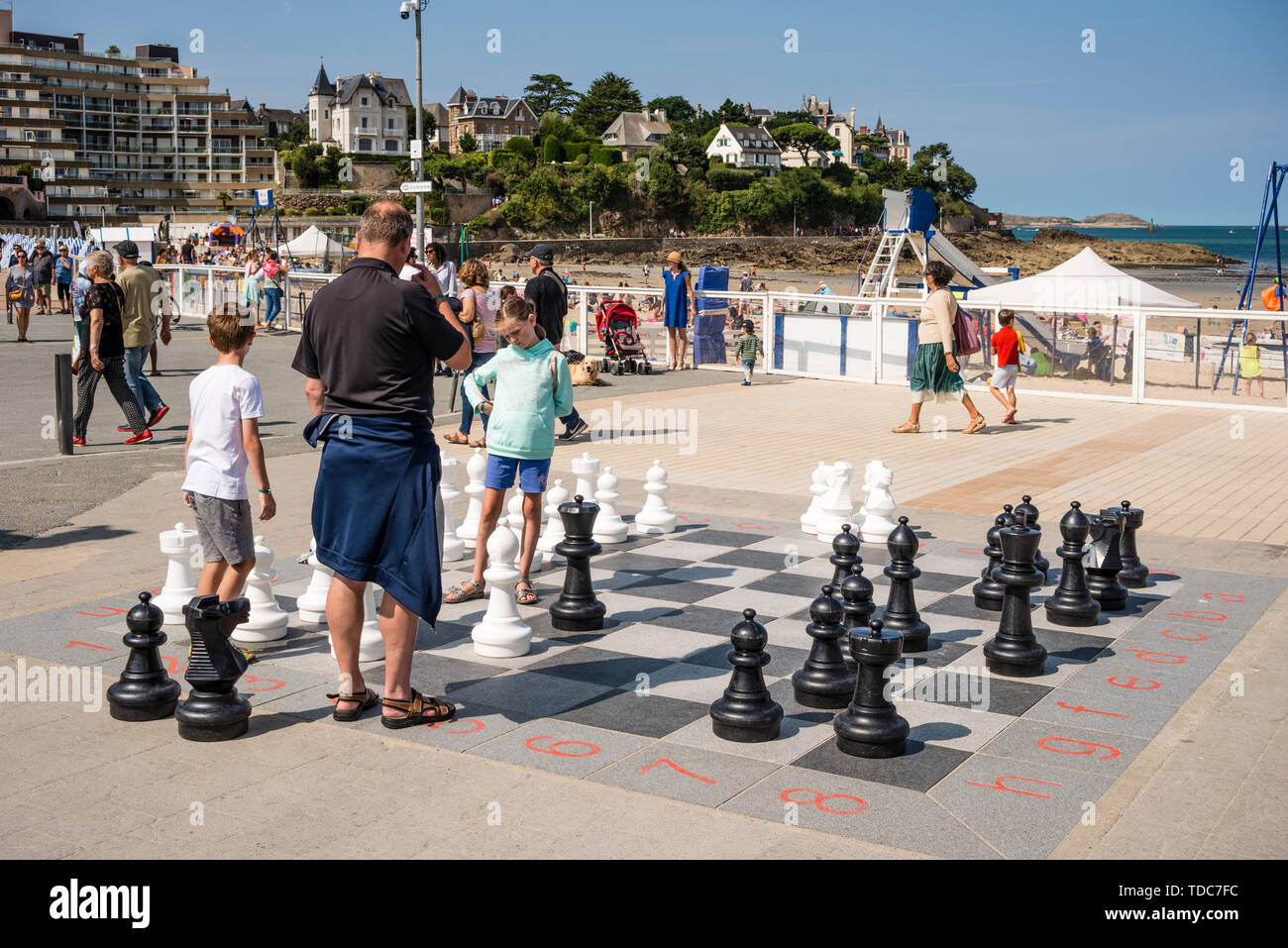 Son père et ses deux jeunes enfants jouer jeu d'échecs géant dans la station balnéaire de Dinard, Bretagne, France Banque D'Images