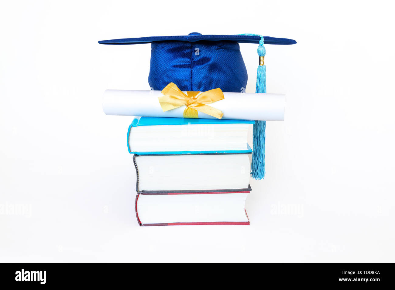 Graduation cap bleu avec du ruban d'or et diplôme sur le dessus du livre isolé sur fond blanc. Concept de l'éducation. Banque D'Images
