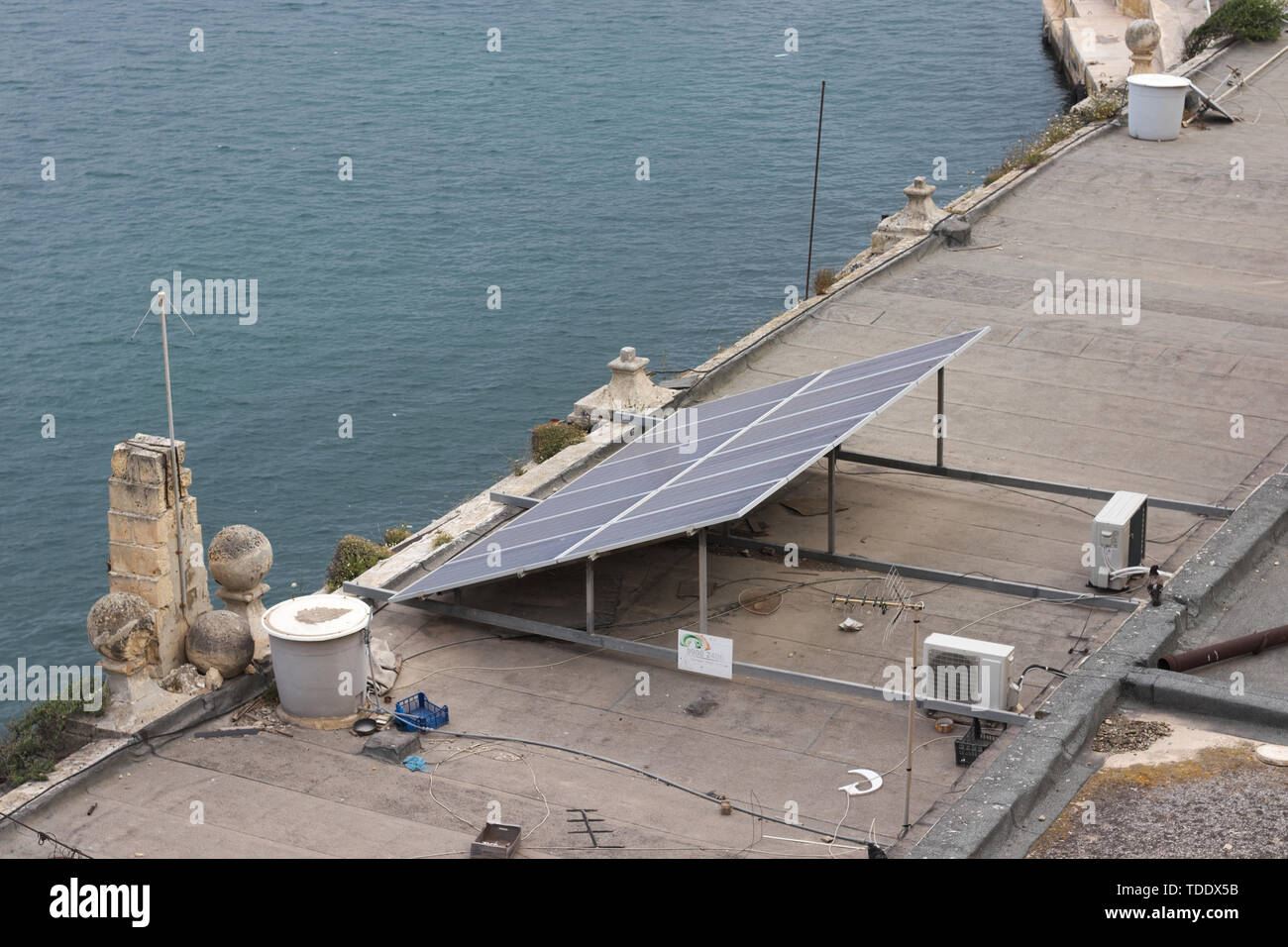 Panneau solaire sur toit sale et malpropre en région méditerranéenne à côté de l'eau. Banque D'Images