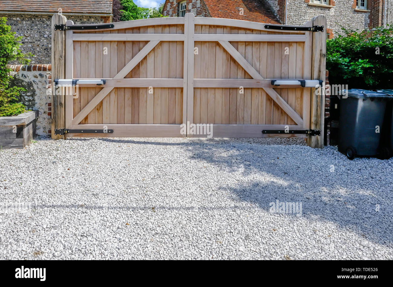 Entrée en bois grande hauteur portails électriques qui sont fermées. À la recherche de l'intérieur avec une voie privée en pierre au premier plan. Banque D'Images