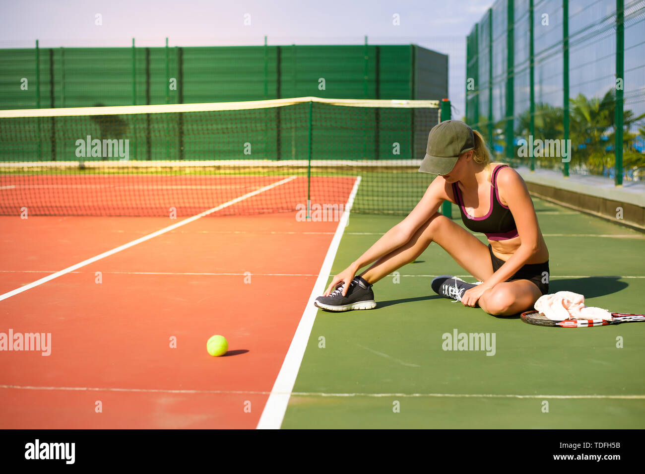 Jeune fille Slim tennis athlète joueur est sur l'open de tennis en été.  Siège et touche le point sensible qui s'étend sur le pied Photo Stock -  Alamy